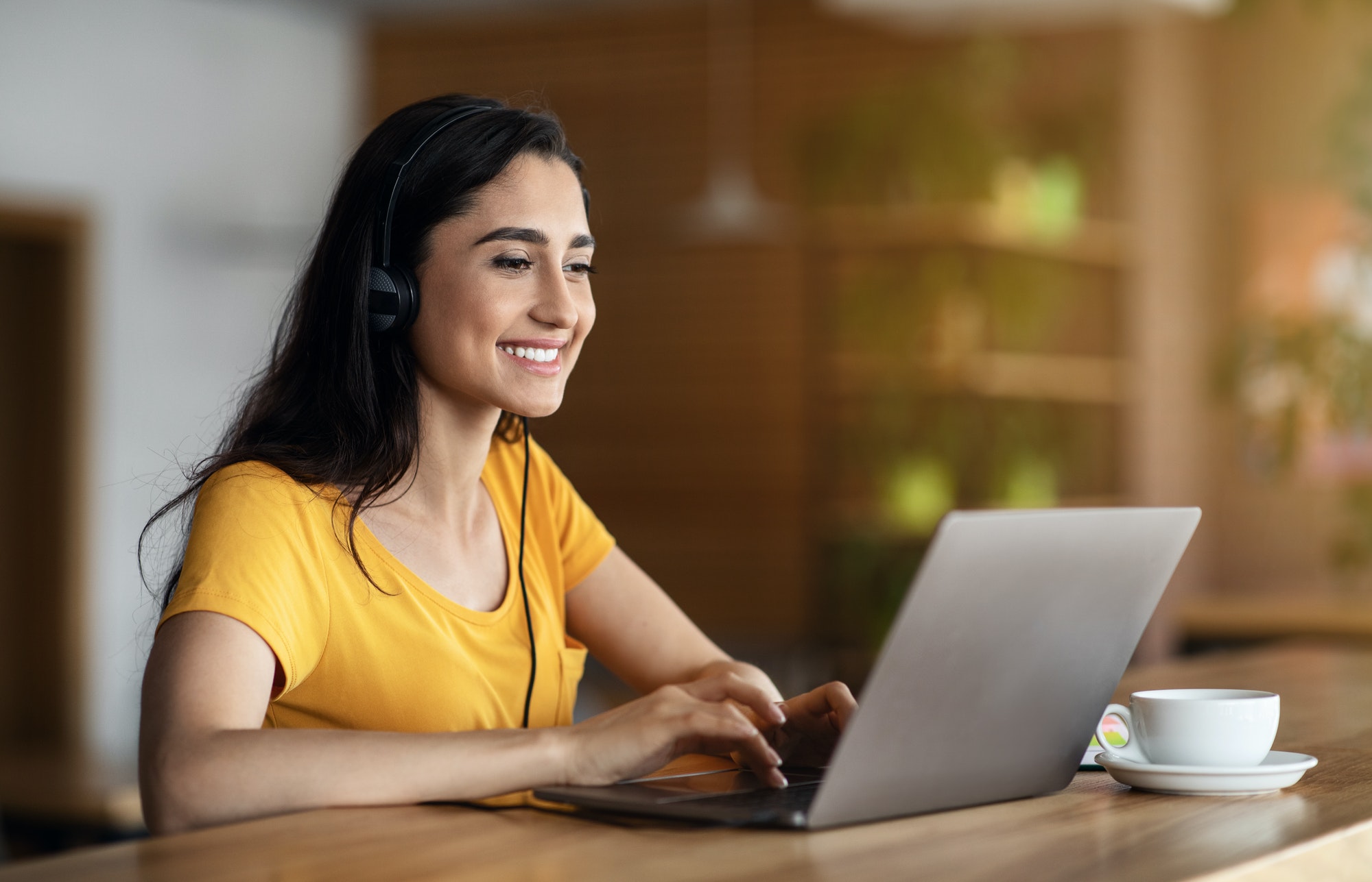 Joyful girl student studying online at cafe