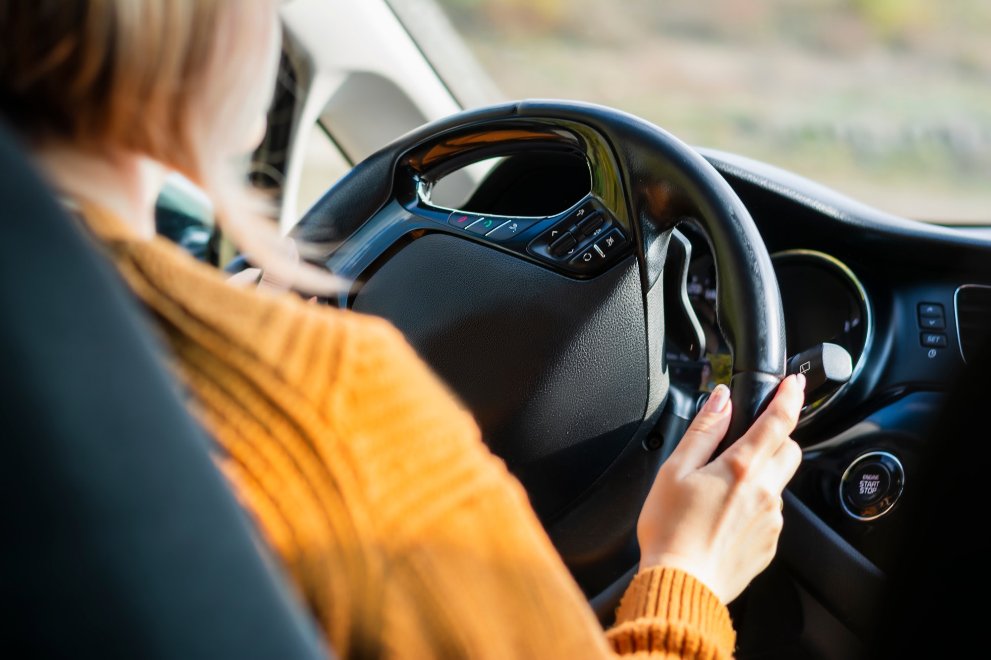 Young woman driver in a car performs tasks necessary to steer the vehicle